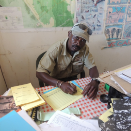 A rhino ranger is sitting at his desk making a report