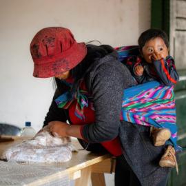 Argentinean artisan at work with her baby on her shoulders. Credit: Nilce Silvina Enrietti