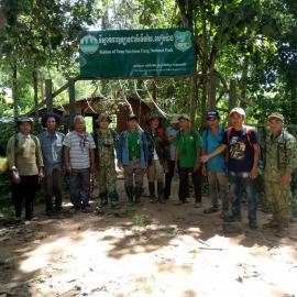 Community wardens and rangers gather around a banner to have their photo taken.